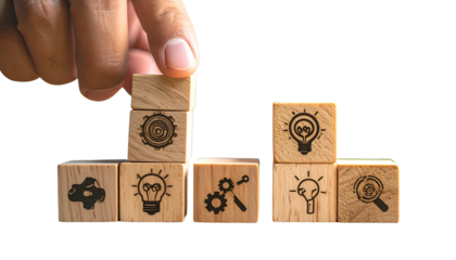 Hand building a tower of wooden blocks with etched business concept symbols