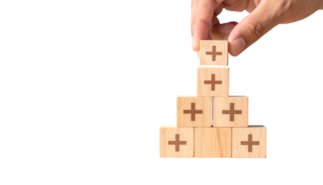 Hand placing wooden block with plus sign atop a pyramid, with black negative space