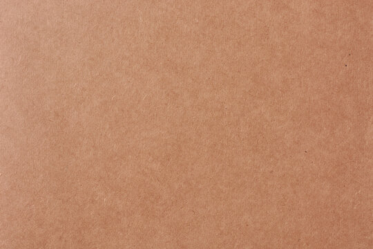 close-up of brown book cover texture, reddish-brown paperboard surface with grainy pattern, abstract background for design in full frame