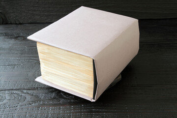 Concept: a book as a key to knowledge, a thick paper book on an old dark wooden table. Books as a reservoir of fundamental scientific knowledge, books as the basis of education and enlightenment.