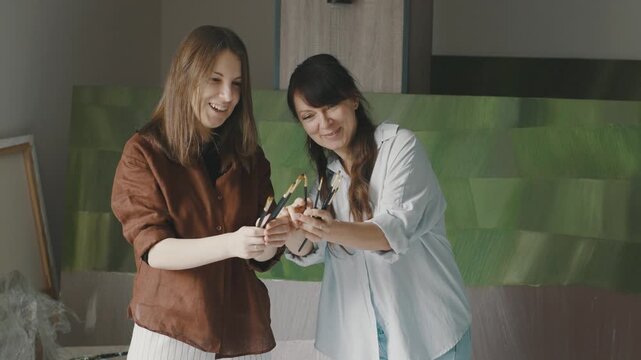 Women create art together in a spacious studio filled with colorful paintings