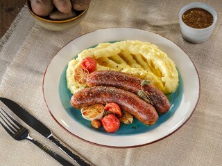 Enjoy a hearty meal of succulent pork sausages paired with creamy mashed potatoes and sweet roasted tomatoes, creating a delightful comfort dish perfect for chilly evenings