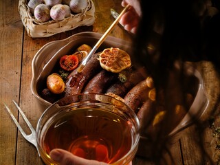 Savor delicious Romanian cuisine with roasted pork sausages surrounded by herbs and garlic. This hearty meal invites warmth and comfort on a chilly winter day