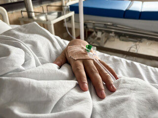 patient hand with iv cannula resting on hospital bed