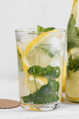 A clear faceted glass with refreshing homemade lemonade, ice cubes, lemon slices
