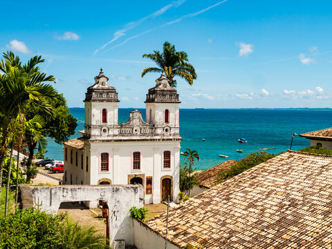 Iconic view of the historic Solar do Unhao complex, featuring the whitewashed colonial chapel and a tall palm tree rising behind it, Salvador, Bahia, Brazil