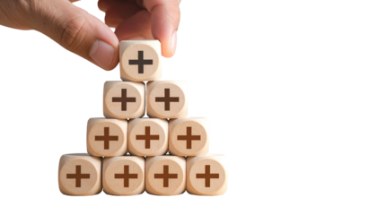 A hand places a plus sign cube on a stack of others, suggesting positive growth