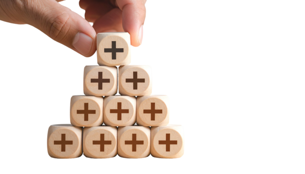 A hand places a plus sign cube on a stack of others, suggesting positive growth