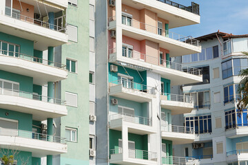 Bright Mediterranean-style apartment blocks stand close together in an Albanian coastal city. Concept of relocation options, holiday stays, and real-estate agency listings in warm seaside environment