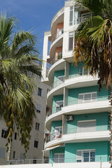 Uniform facades with large windows create a bright housing line above an Albanian road. This residential area fits rental markets, relocation plans, agency portfolios, and property purchase searches.