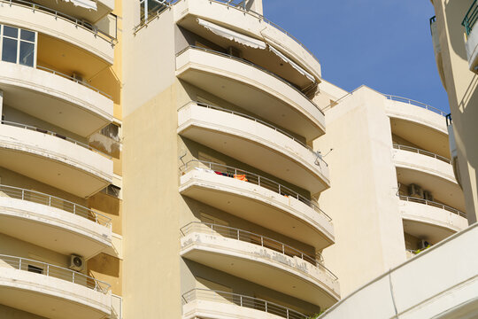 Light-toned Mediterranean apartment building in Albanian city, clean architectural lines, terraces. Great for rental listings, buying opportunities, relocation guides, vacation planning, and agencies