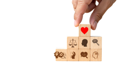 A hand placing a heart-symbol block atop a tiered stack of other symbol-etched blocks