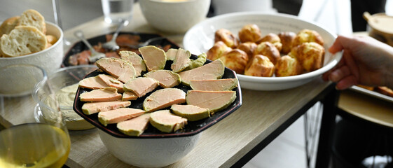Scène d'apéritif composé de plusieurs verres de vin blanc et d'assiettes de foie gras et saumon...