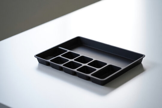 Black plastic desk organizer tray with compartments sitting on white table surface for office supplies or drawer divider at home 150 chars