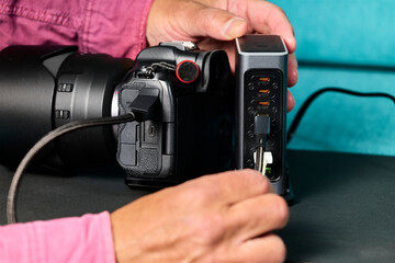 Battery charger. Man's hand connecting a USB cable from a camera to a multi-battery charger with several USB ports.