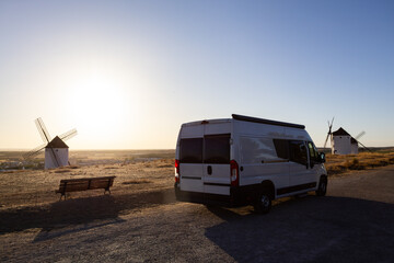 Camper van traveling through Mota del Cuervo windmills at sunset