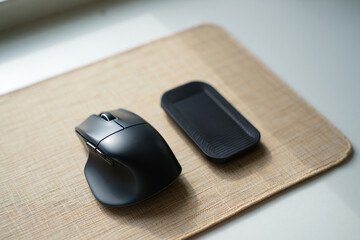 Wireless Computer Mouse and Wrist Rest on Tan Mouse Pad on Top of White Table for Ergonomic Computing and Comfortable Use