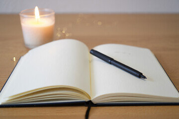 Open Notebook on Wooden Desk with Burning Candle for Writing Ideas and Journaling in Calm Atmosphere as Motivational and Creative Practice