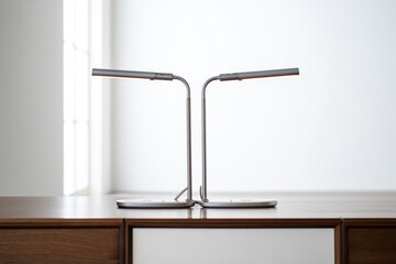 Modern Silver Desk Lamps Providing Task Lighting in Minimalist Workspace with Wooden Cabinet for Interior Design and Office Decor