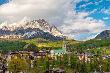 Scenic view of Cortina d'Ampezzo with alpine village, church tower and snow covered Dolomiti Alps mountains. Italian Dolomites in Belluno region, Italy. Travel and touristic destination in winter