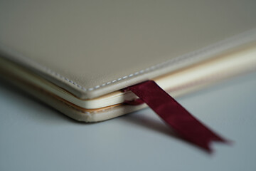 Closeup of Notebook with Cream Cover and Red Bookmark on Neutral Surface Offering Blank Pages for Ideas and Stories for Your Next Great Writing Project