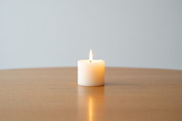 Burning Candle on Wooden Desk Top in Bright Room Interior with a White Wall in Minimalist Style at Home or Office Space 150chr