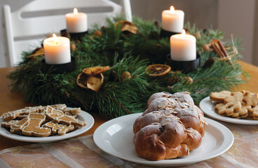 Traditional Czech and Slovak Christmas sweet plaited bread called vanocka (in Slovak vianocka), Christmas cookies and a Christmas advent wreath with four burning candles on wooden table.