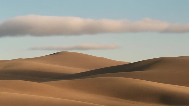 A tranquil and minimalistic desert scene featuring smooth, rolling sand dunes under a calm sky with a single cloud formation