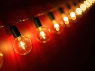 Close up of warm glowing string light bulbs hanging against a dark red background creating a festive and cozy atmosphere