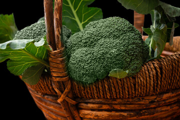 Fresh broccoli and greens in a rustic woven basket captured in natural light