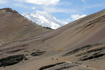 The snow-covered Auzangate mountain looming over hikers going to see the Rainbow Mountain (Vinicuna).  Located in Peru.