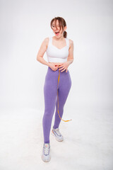 Beautiful sports girl measuring her waist with a measure tape isolated on a white background. Attractive young woman in sportswear posing in the studio.