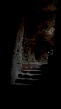 Ancient stone staircase leading upward inside Fabrika Hill Cave Complex, dim natural light revealing rough carved walls and creating a mysterious underground atmosphere with depth and shadows