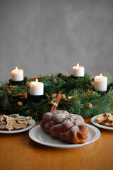 Traditional Czech and Slovak Christmas sweet plaited bread called vanocka (in Slovak vianocka), Christmas cookies and a Christmas advent wreath with four burning candles on wooden table.