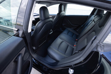 Black leather rear seats with seats belt. Modern electric car interior. Back passenger seats modern electric car. Rear passenger seats. Electric car interior. Leather interior design.