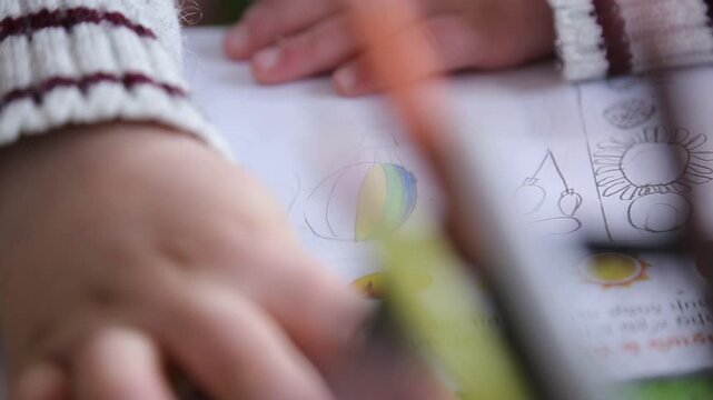 Close up shots of children's hands drawing and coloring. One kid colors a worksheet with a blue pencil, while a girl draws on white paper with a wooden pencil.

