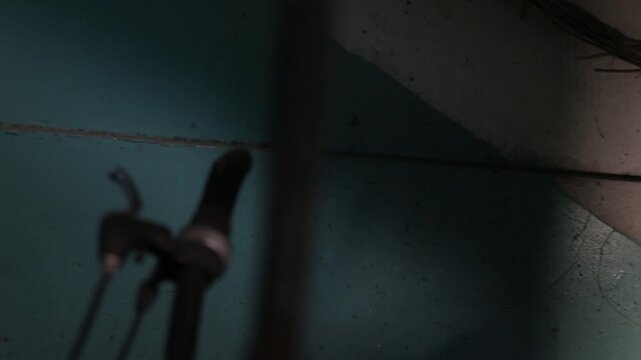 Mysterious shadow of a person walking with a bicycle cast on a textured urban wall. Person pushes bike past metal fence in dark gritty alleyway.

