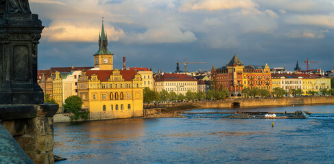 Fototapeta premium Prague Vltava River panorama with historic yellow clock tower building and colorful waterfront architecture, Czech Republic Old Town scenic riverside view