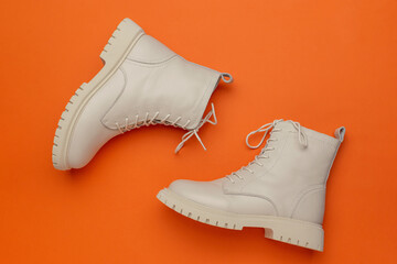 Chic White Combat Boots on Vibrant Orange Background: Contemporary Fashion Footwear