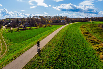 Cyclist riding a bicycle along a flood embankment near the Vistula River in the Ispina area, Poland. Recreation, fitness, and outdoor travel concept.