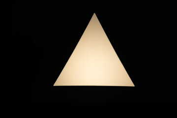 Fototapeta premium An abstract geometric white triangle illuminated against a solid black background, creating a minimalist and high-contrast composition. Ideal for design, concepts, and backgrounds.