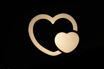 Two glowing heart shapes, one large outline and one smaller solid, stand out against a dark background, symbolizing love, affection, and connection, perfect for romantic themes or Valentine's Day.