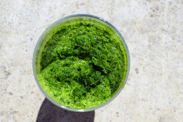 Top view of green herb smoothie showing creamy texture with visible leafy green specks. Illustrates blended vegetable drink, healthy beverage choice, fresh greens consumption, and celery use.