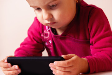 Child smiling brightly in a close-up portrait with her gadget.