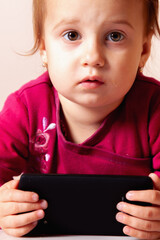 Smiling child holding a black tablet during playtime.