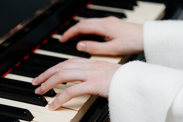 Obraz premium female pianist hands on black and white piano keyboard, close-up view, young woman playing piano, professional musician