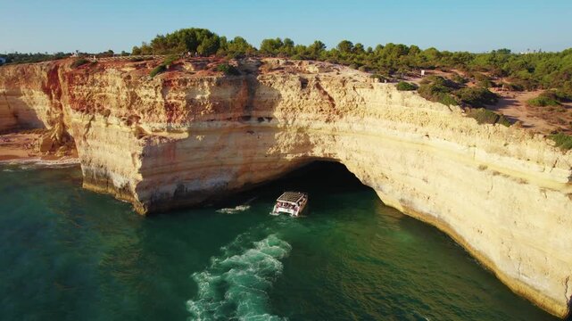 Aerial of a boat coming out of a Benagil cave in southern coast of Portugal