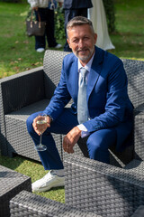Elegant man in blue suit relaxing outdoors with a glass of wine