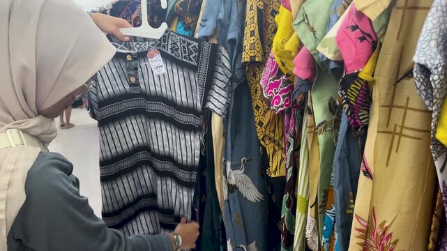 A woman selects batik fabric while shopping in a Yogyakarta store in the afternoon
