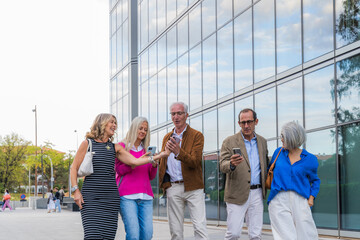 Mature friends sharing cell phones after work